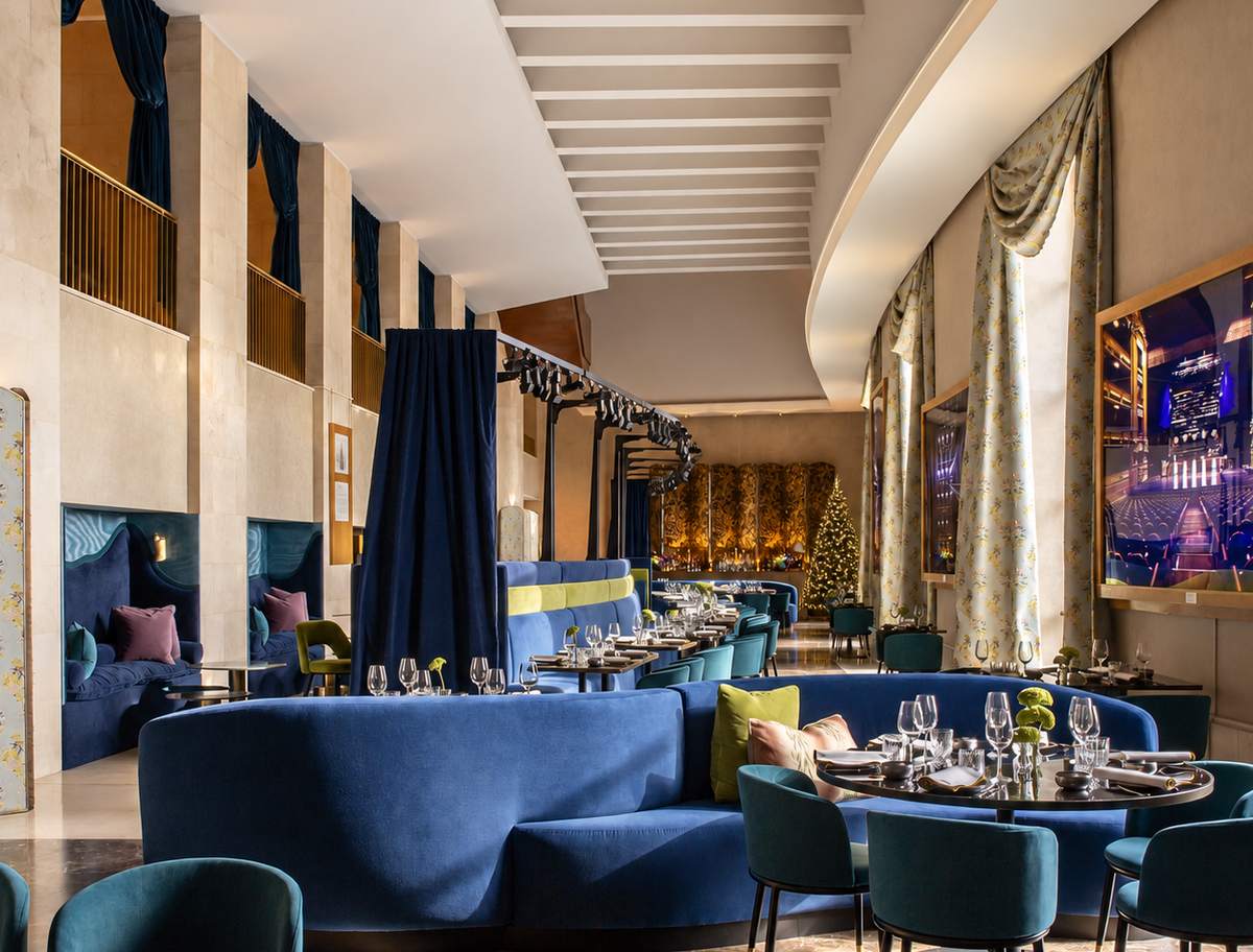 Salón de Papagena con los sofás azules, las mesas montadas y un árbol de Navidad iluminado al fondo
